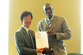 Masato Masuda, Executive Member of the Board of Trustees, receiving the Certification from Alton Grizzle
