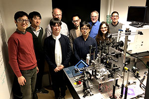 固体微粒子加速実験装置の後ろに並ぶ国際協力実験関係者