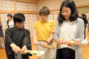 留学生が扇の開き方を教えてもらう様子