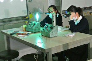 簡易分光器で水銀灯を観察している生徒