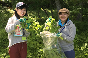 駆除した外来種植物を掲げる学生