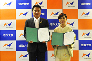 協定書には、西岡市長（左）、田中総長によって署名がされた